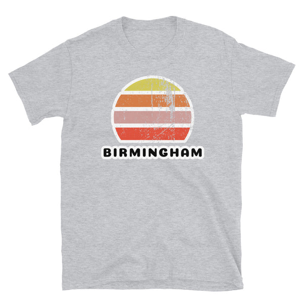 Features a distressed abstract retro sunset graphic in yellow, orange, pink and scarlet stripes rising up from the famous Birmingham place name on this sport grey t-shirt