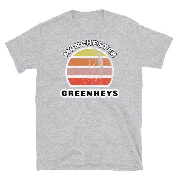 Distressed style abstract retro sunset graphic in yellow, orange, pink and scarlet stripes. The name of Manchester is displayed at the top wrapped around the sunset. Below the retro sunset design is the famous Manchester place name of Greenheys on this light grey cotton t-shirt.