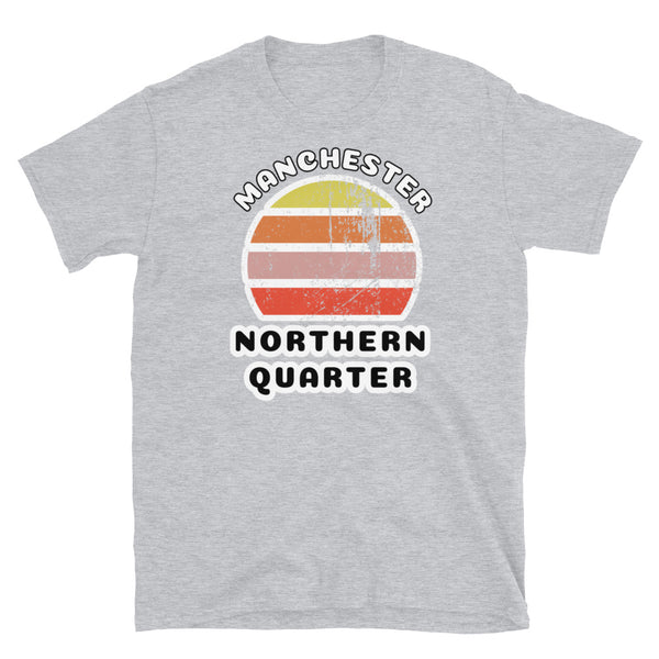 Distressed style abstract retro sunset graphic in yellow, orange, pink and scarlet stripes. The name of Manchester is displayed at the top wrapped around the sunset. Below the retro sunset design is the famous Manchester place name of Northern Quarter on this light grey cotton t-shirt.