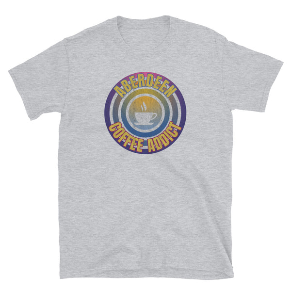 Concentric circular design of retro 80s metallic colours and the slogan Aberdeen Coffee Addict with a coffee cup silhouette in the centre. Distressed and dirty style image for a vintage Retrowave look on this light grey cotton t-shirt by BillingtonPix