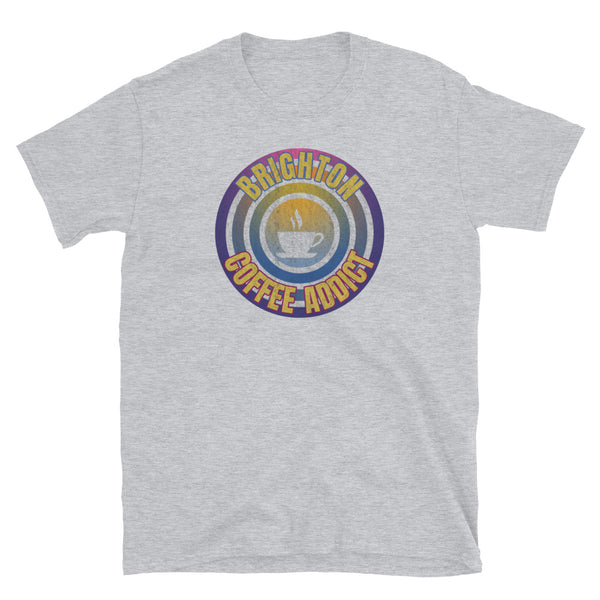 Concentric circular design of retro 80s metallic colours and the slogan Brighton Coffee Addict with a coffee cup silhouette in the centre. Distressed and dirty style image for a vintage Retrowave look on this light grey cotton t-shirt by BillingtonPix