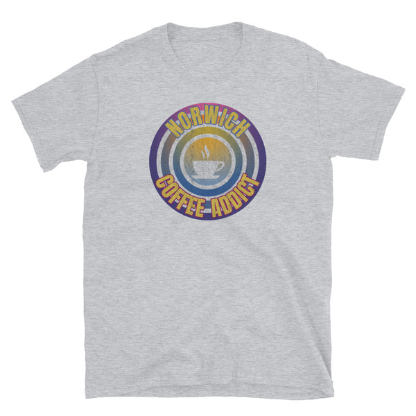 Concentric circular design of retro 80s metallic colours and the slogan Norwich Coffee Addict with a coffee cup silhouette in the centre. Distressed and dirty style image for a vintage Retrowave look on this light grey black cotton t-shirt by BillingtonPix