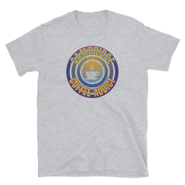 Concentric circular design of retro 80s metallic colours and the slogan Cambridge Coffee Addict with a coffee cup silhouette in the centre. Distressed and dirty style image for a vintage Retrowave look on this light grey cotton t-shirt by BillingtonPix