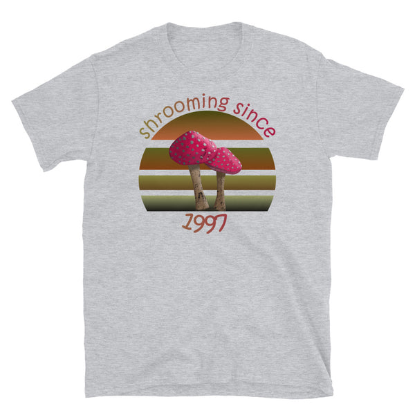Shrooming since 1997 cute Goblincore style design with two red fly agaric mushrooms with distressed look against a multi-toned nature colour palette abstract vintage sunset design on this sport grey cotton t-shirt by BillingtonPix