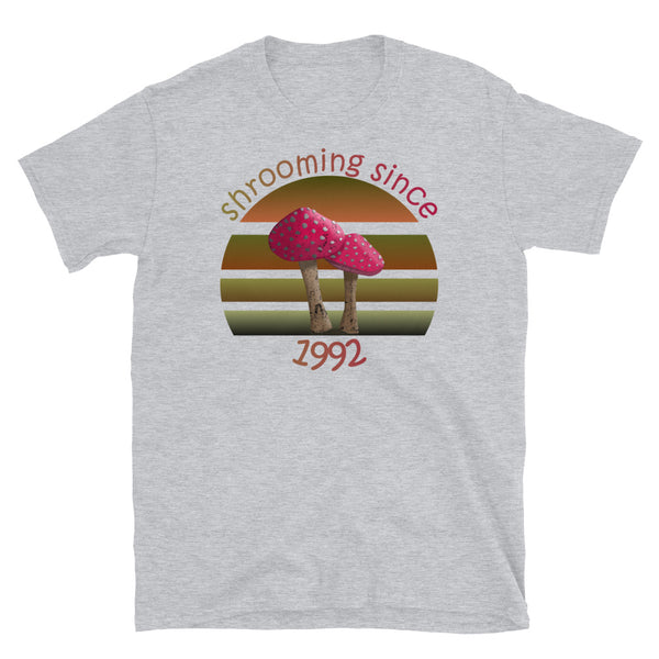 Shrooming since 1992 cute Goblincore style design with two red fly agaric mushrooms with distressed look against a multi-toned nature colour palette abstract vintage sunset design on this sport grey cotton t-shirt by BillingtonPix