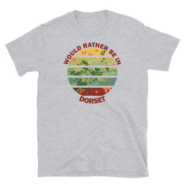 Cottagecore style floral and butterfly design within a Vintage Sunset abstract shape in tones of crimson, teal, green, mustard and yellow stripes with the slogan Would Rather Be in Dorset on this sport grey cotton t-shirt by BillingtonPix