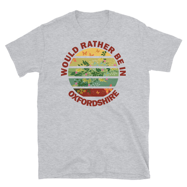 Cottagecore style floral and butterfly design within a Vintage Sunset abstract shape in tones of crimson, teal, green, mustard and yellow stripes with the slogan Would Rather Be in Oxfordshire on this sport grey cotton t-shirt by BillingtonPix