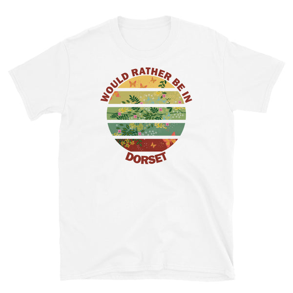 Cottagecore style floral and butterfly design within a Vintage Sunset abstract shape in tones of crimson, teal, green, mustard and yellow stripes with the slogan Would Rather Be in Dorset on this white cotton t-shirt by BillingtonPix